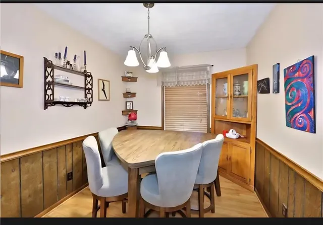 a dining room with wooden floor and chandelier