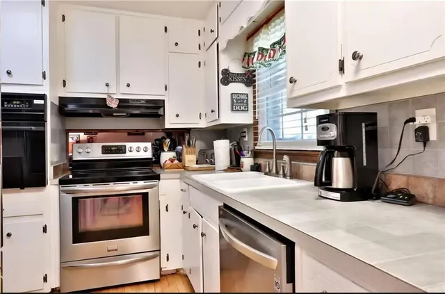 a kitchen with stainless steel appliances granite countertop a stove and white cabinets