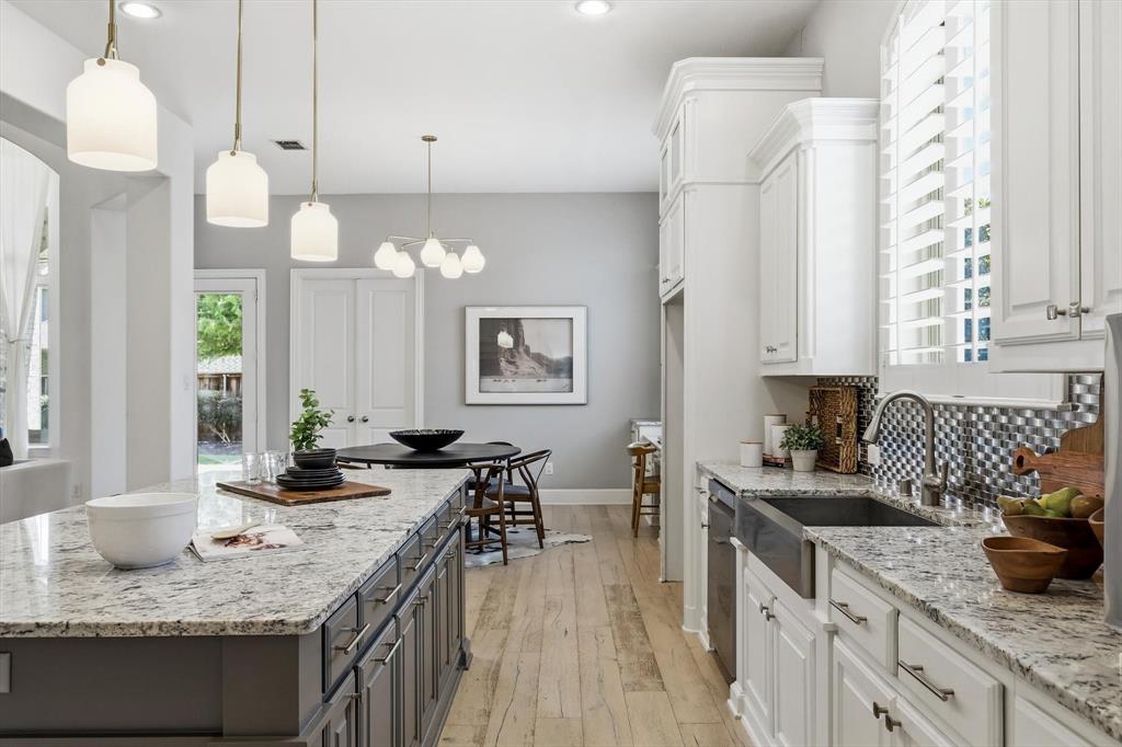 1933 Snapdragon Road Frisco, TX 75033 - Photo 10 of 40 Spacious kitchen featuring a large island with a light-toned countertop, white cabinetry with crown molding, a deep-basin sink, and light wood-finish flooring
