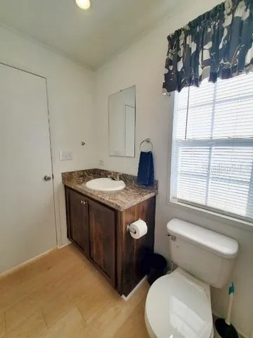 a bathroom with a granite countertop sink and a toilet