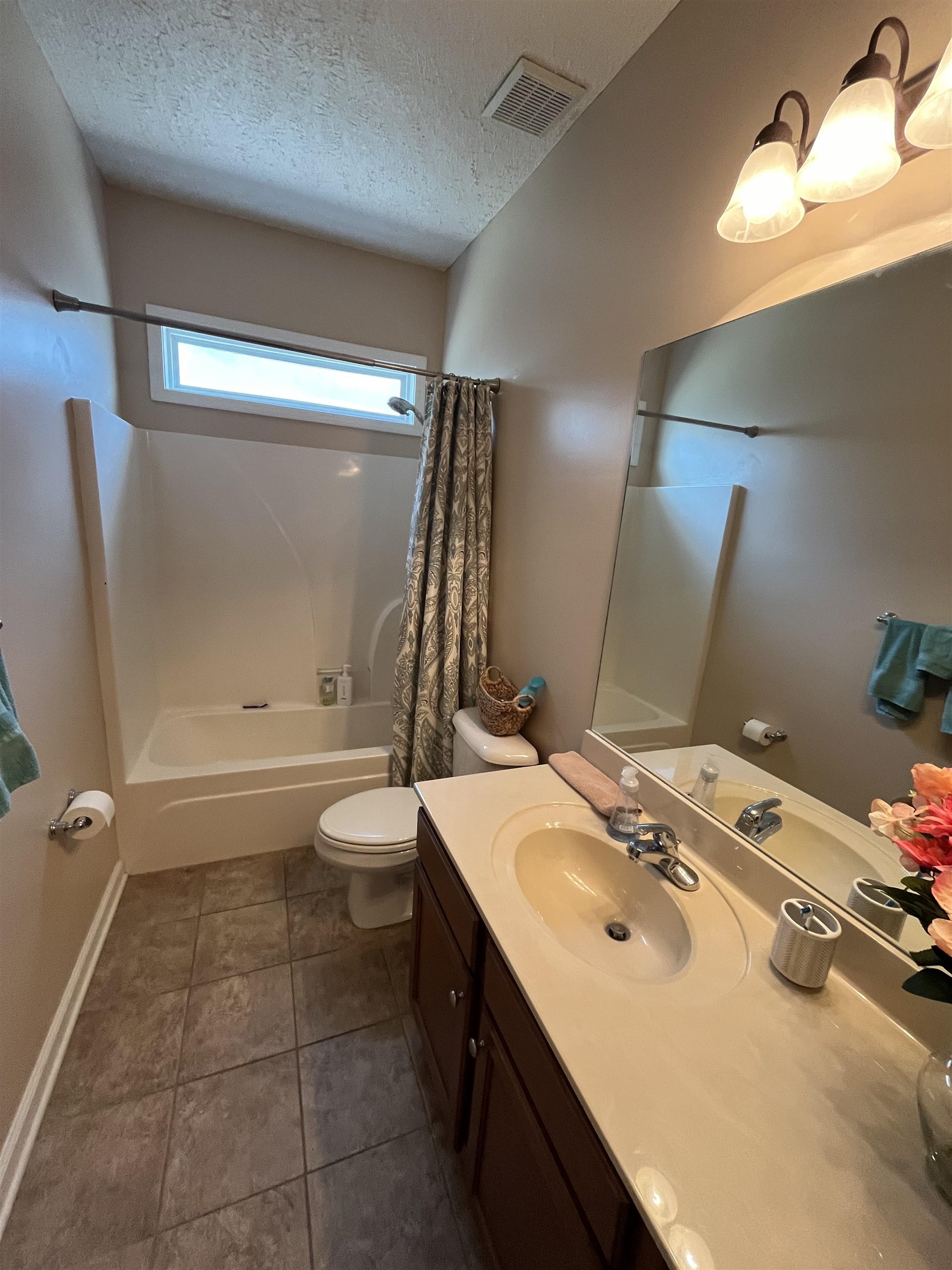 5485 Shipp Road Millington, TN 38053 - Photo 11 of 17 Full bathroom featuring a textured ceiling, toilet, vanity, shower / bath combo with shower curtain, and tile patterned floors