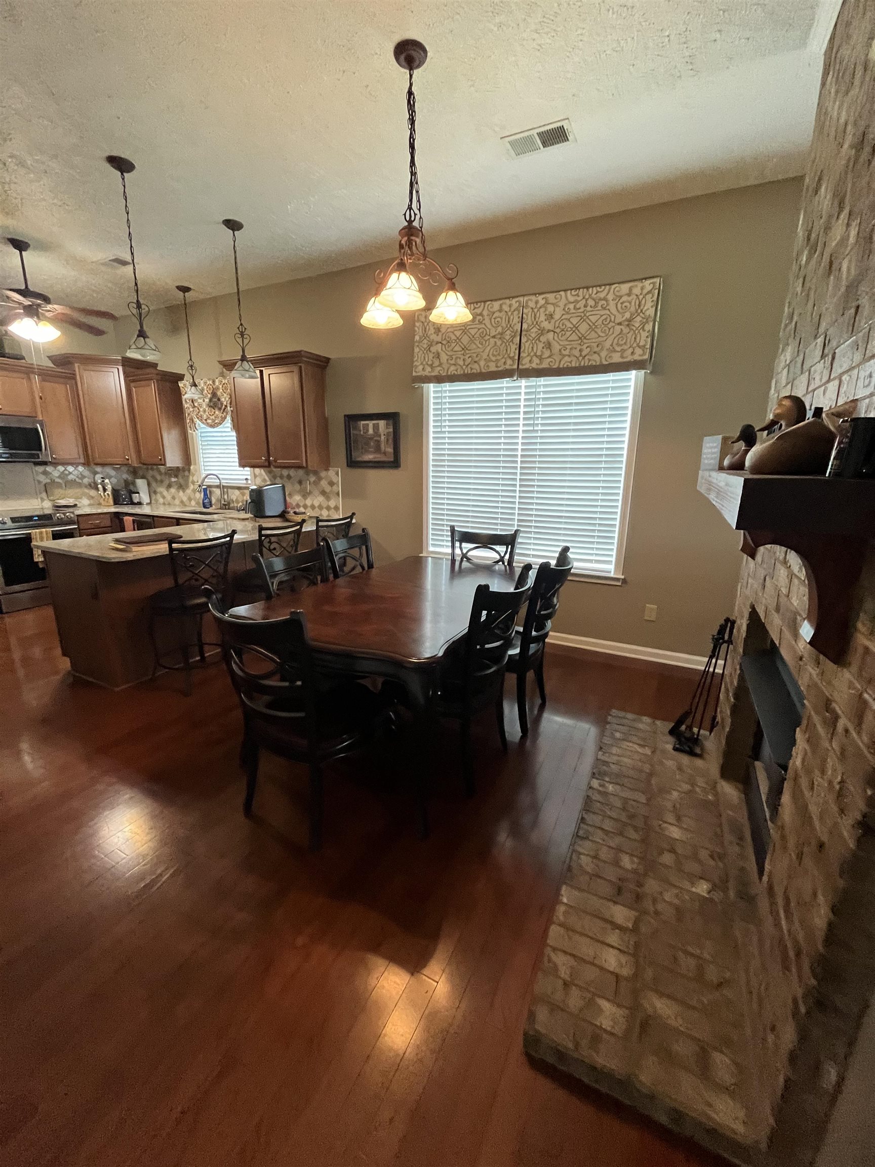 5485 Shipp Road Millington, TN 38053 - Photo 4 of 17 Dining room featuring dark hardwood / wood-style flooring, a textured ceiling, a stone fireplace, and ceiling fan
