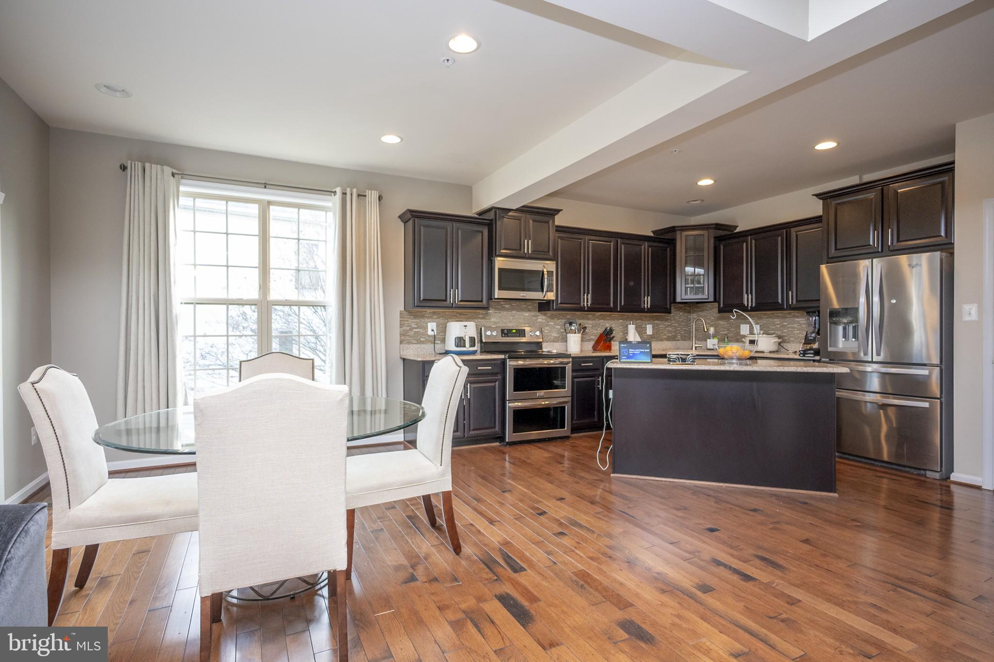 2703 Swann Wing Court Lanham, MD 20706 - Photo 16 of 36 a kitchen with stainless steel appliances kitchen island granite countertop wooden floors and wooden cabinets