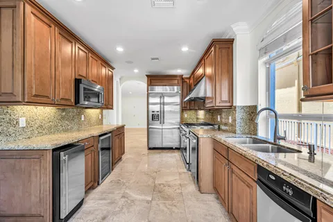 a kitchen with stainless steel appliances granite countertop wooden cabinets a sink dishwasher a stove and a refrigerator
