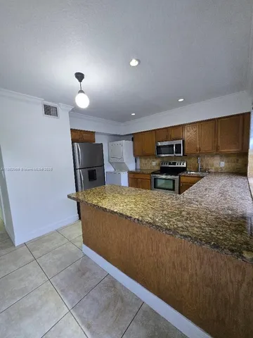 a living room with stainless steel appliances kitchen island granite countertop a couch and a counter space