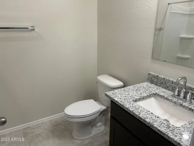 a bathroom with a granite countertop toilet and sink