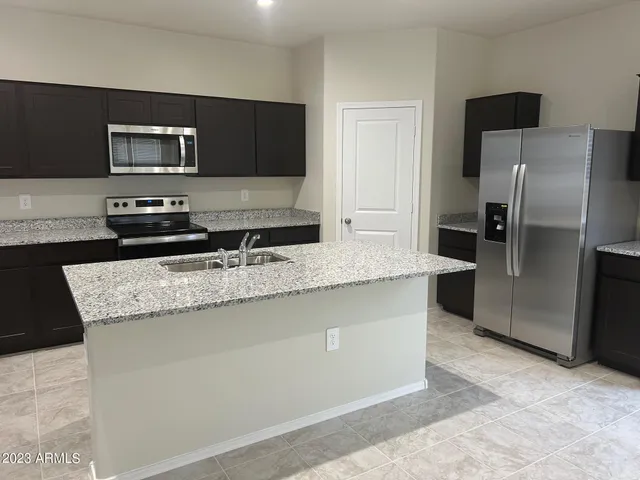 a kitchen with granite countertop a refrigerator and a stove top oven