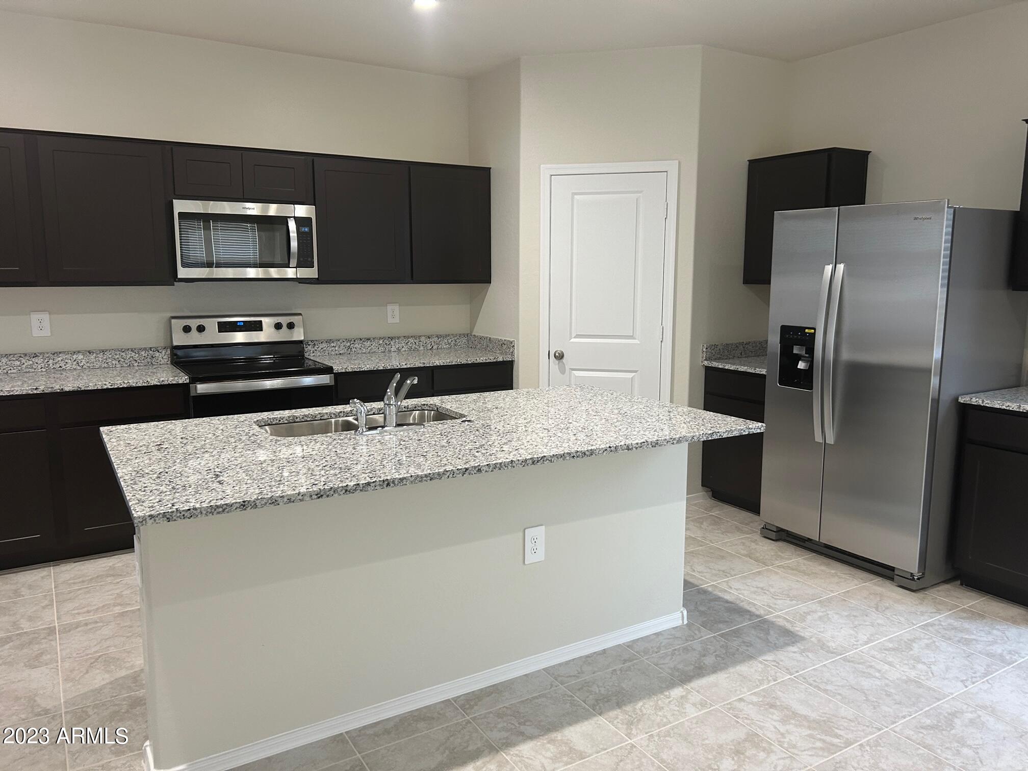 5119 East Emery Road San Tan Valley, AZ 85143 - Photo 4 of 19 a kitchen with granite countertop a refrigerator and a stove top oven