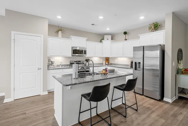 a kitchen with kitchen island granite countertop a refrigerator and a stove top oven