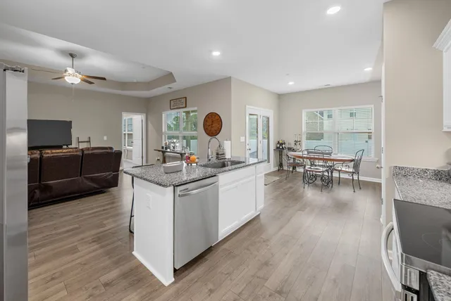 a living room with stainless steel appliances granite countertop furniture and wooden floors