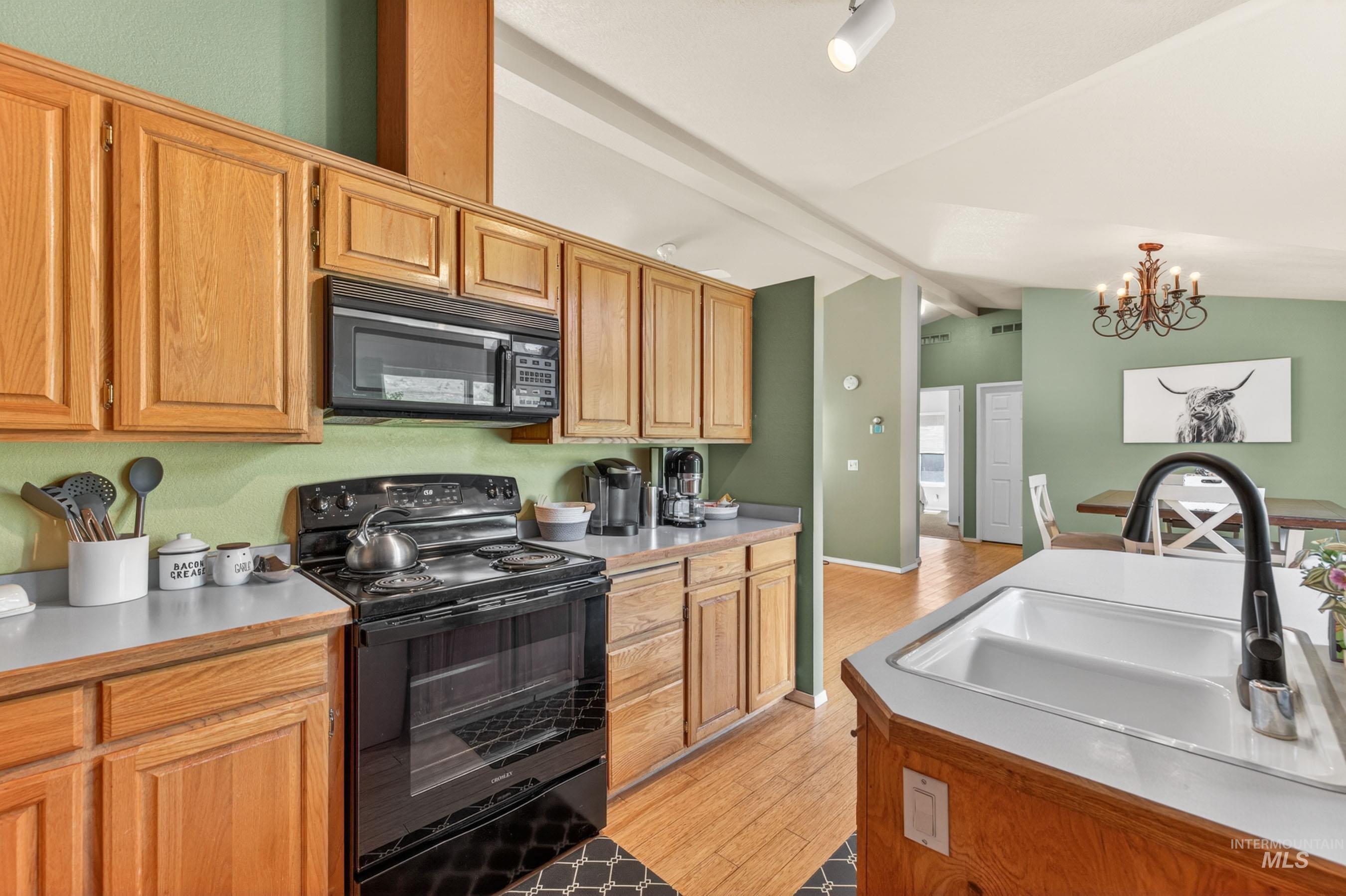 151 Cow Creek Road Lucile, ID 83542 - Photo 19 of 50 Kitchen featuring wood cabinetry, black appliances, light countertops, wood-finish flooring, and a double basin sink with a gooseneck faucet
