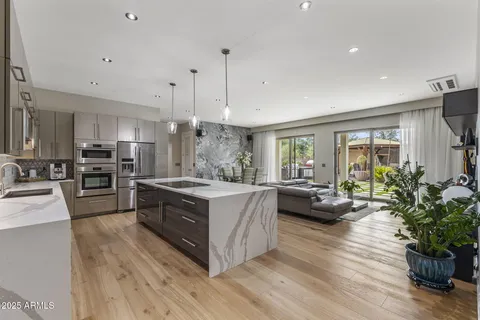 a large kitchen with stainless steel appliances lots of counter space a sink refrigerator and wooden floor