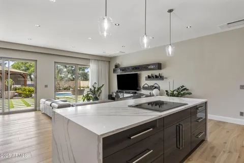a kitchen with a stove a sink a kitchen island with a large window and wooden floor