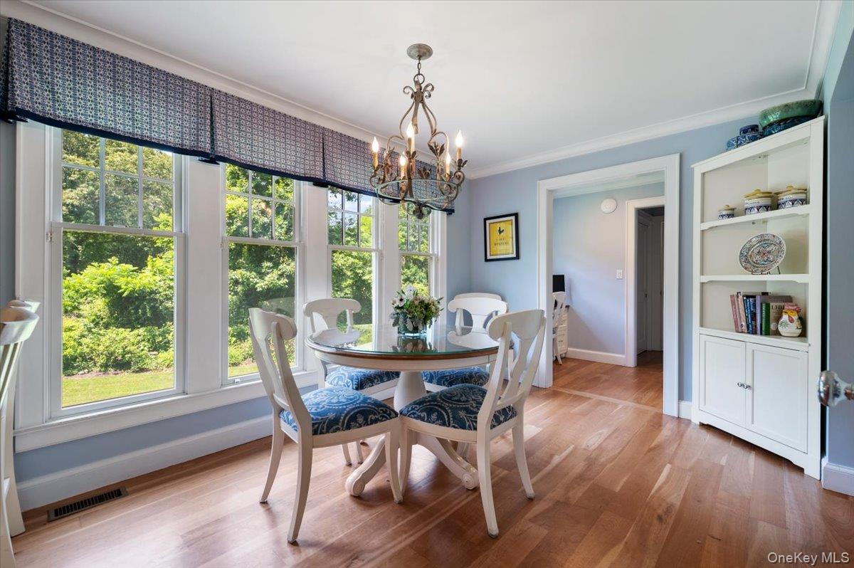 5 Fox Hunt Court Cold Spring Harbor, NY 11724 - Photo 15 of 42 Dining area featuring hardwood flooring, extensive window array with patterned valances, a decorative chandelier, and a built-in corner display cabinet
