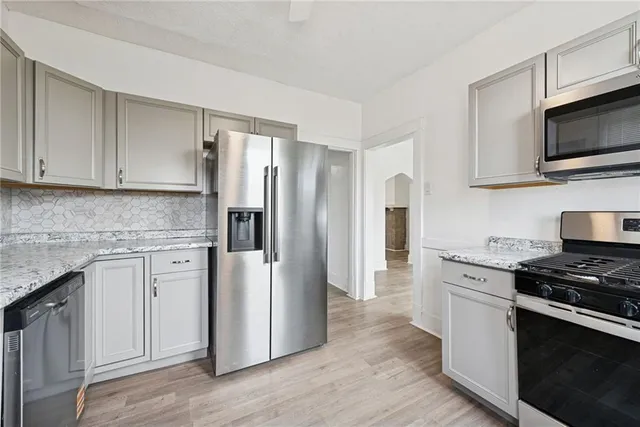 a kitchen with stainless steel appliances white cabinets white stove a sink and a refrigerator