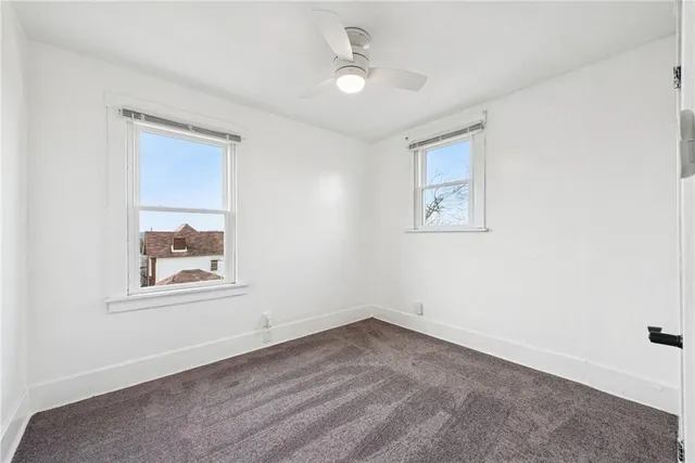 an empty room with a window and a ceiling fan