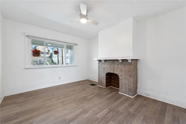 an empty room with wooden floor fireplace and fan