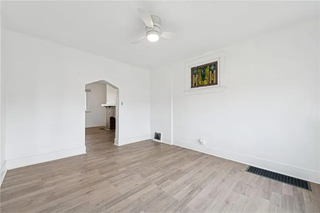 an empty room with wooden floor and a ceiling fan