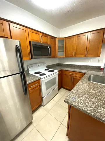 a kitchen with granite countertop a sink a stove and cabinets