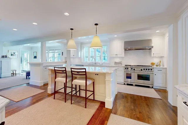 a kitchen with stainless steel appliances a stove a sink dishwasher a oven with white cabinets and wooden floor