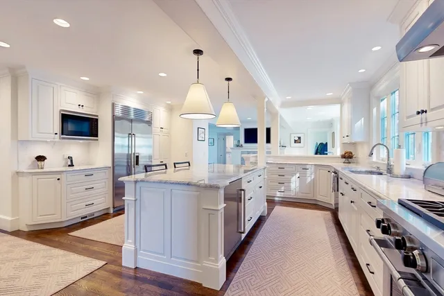 a kitchen with kitchen island granite countertop lots of white stainless steel appliances and white cabinets