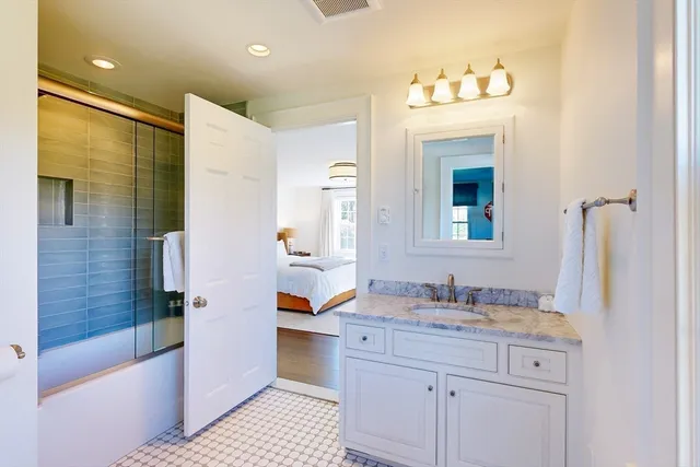 a bathroom with a granite countertop sink a mirror a bathtub and shower