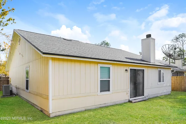 a view of a backyard with white wall and a large tree