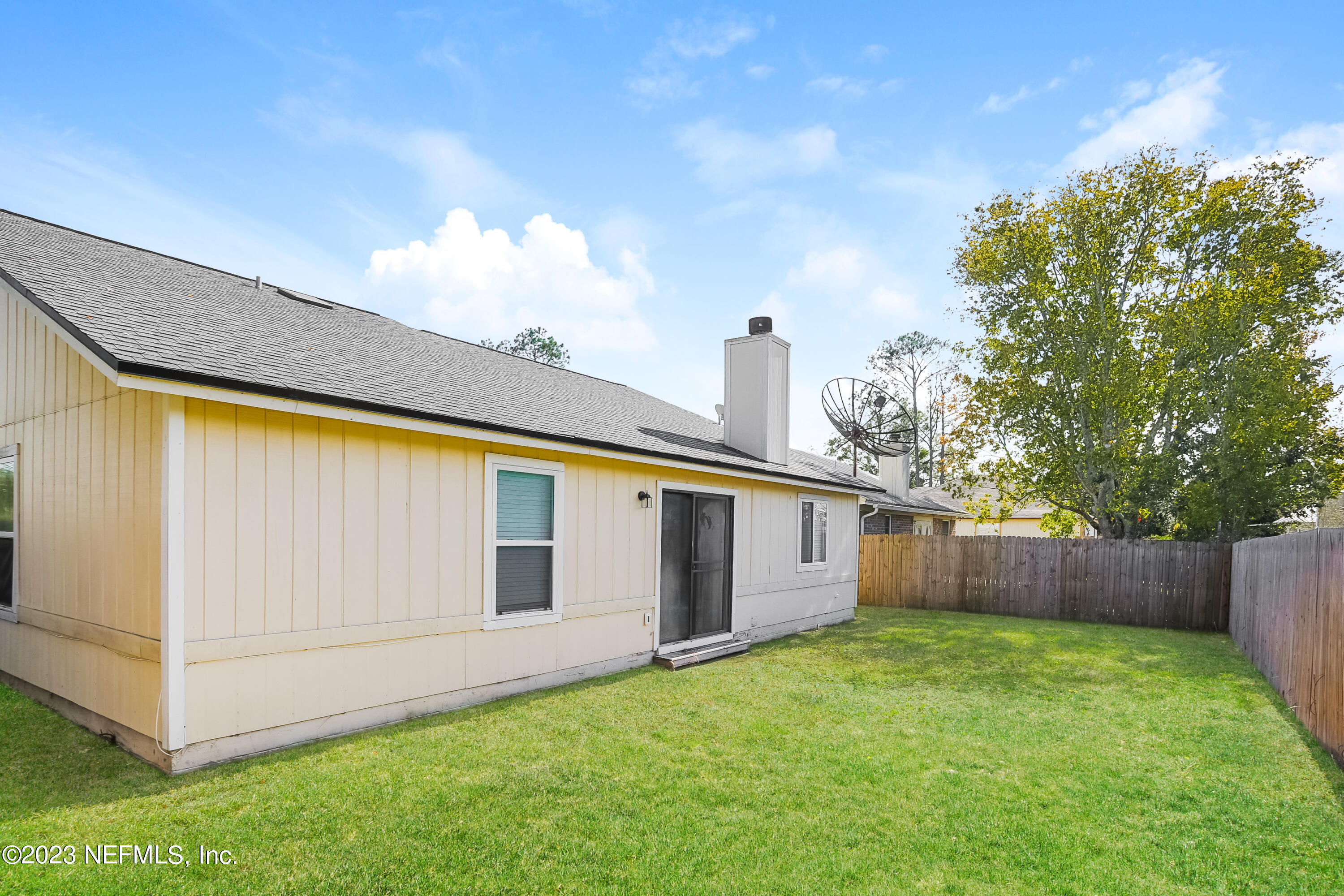 7684 Collins Ridge Boulevard Jacksonville, FL 32244 - Photo 14 of 15 a view of a backyard with white wall and a large tree