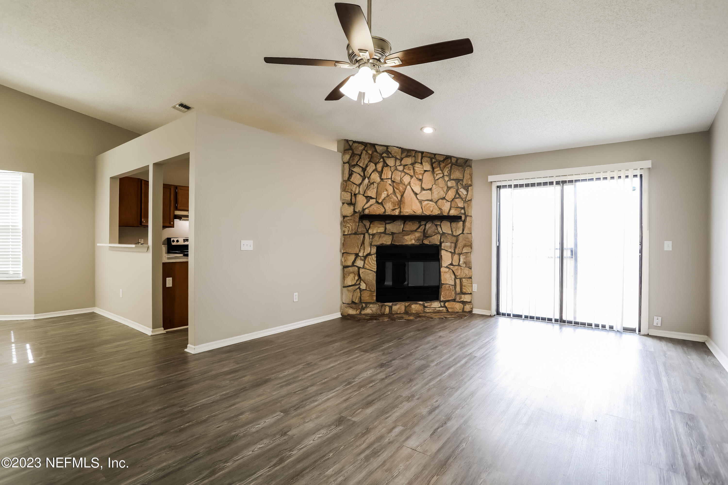 7684 Collins Ridge Boulevard Jacksonville, FL 32244 - Photo 4 of 15 an empty room with wooden floor a ceiling fan a fireplace and windows