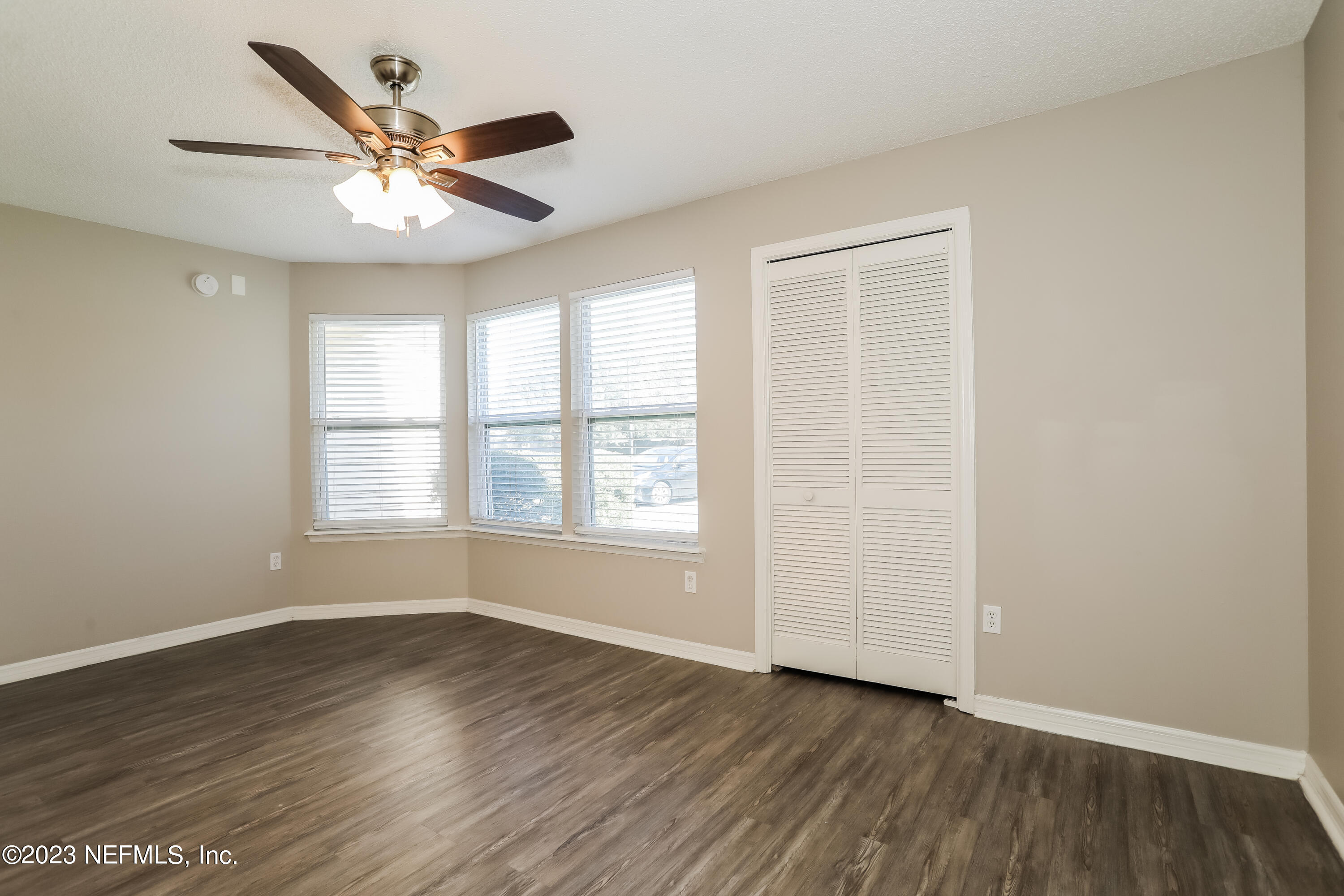 7684 Collins Ridge Boulevard Jacksonville, FL 32244 - Photo 8 of 15 an empty room with wooden floor chandelier fan and windows