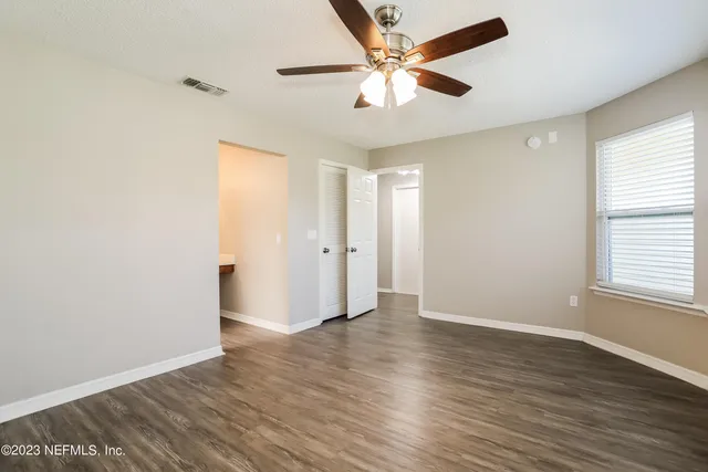 an empty room with wooden floor and windows