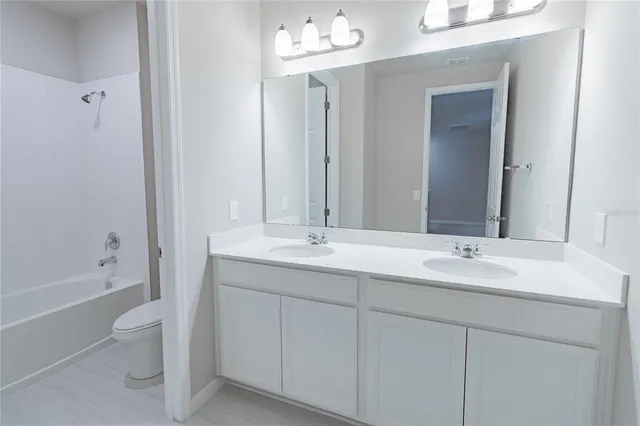 a bathroom with a double vanity sink mirror and toilet
