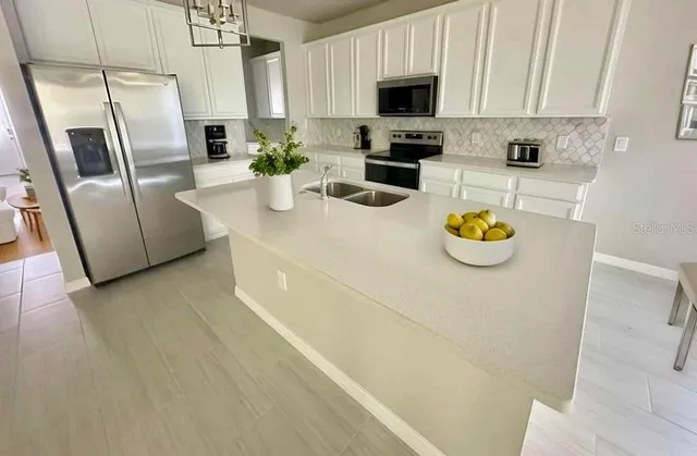 a kitchen with stainless steel appliances a sink a microwave a refrigerator a stove a microwave and cabinets