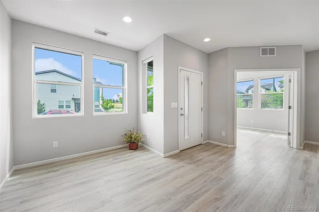 an empty room with wooden floor and windows