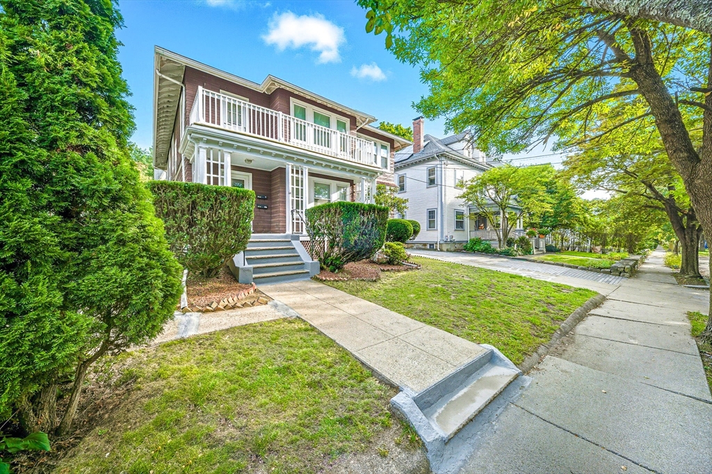 a front view of a house with garden and trees