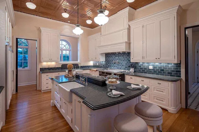 a kitchen with a sink a stove cabinets and wooden floor