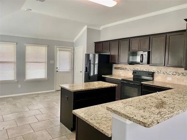 a kitchen with granite countertop a sink a stove a refrigerator and island