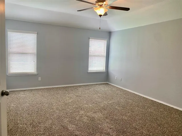 an empty room with windows and fan
