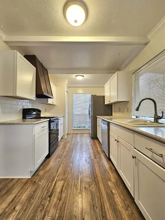 a kitchen with wooden floor and stainless steel appliances