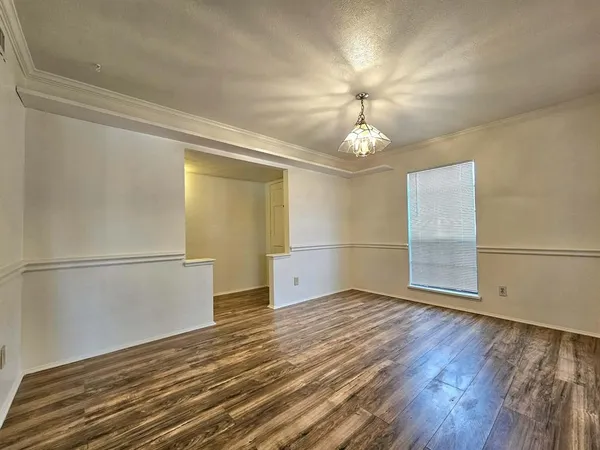 an empty room with wooden floor cabinet and windows