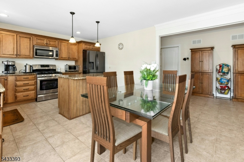 33 Stanton Street Clark, NJ 07066 - Photo 8 of 37 a kitchen with stainless steel appliances granite countertop a table chairs and a refrigerator