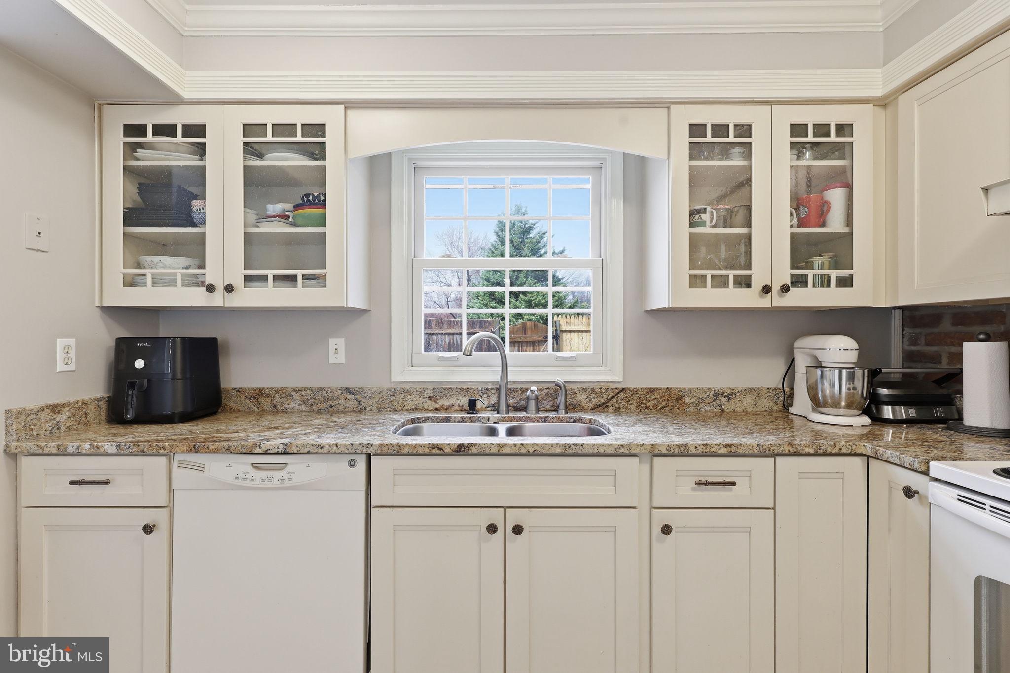 8222 Carrleigh Parkway, Unit 12 Springfield, VA 22152 - Photo 11 of 22 a kitchen with kitchen island granite countertop a sink cabinets and window