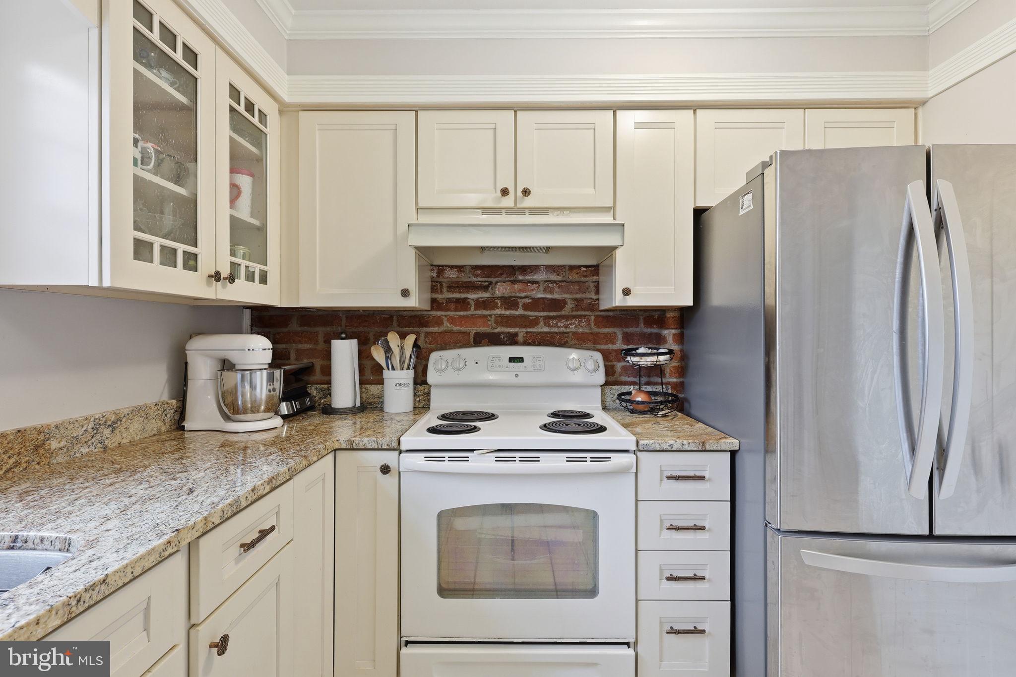 8222 Carrleigh Parkway, Unit 12 Springfield, VA 22152 - Photo 13 of 22 a kitchen with granite countertop white cabinets and refrigerator