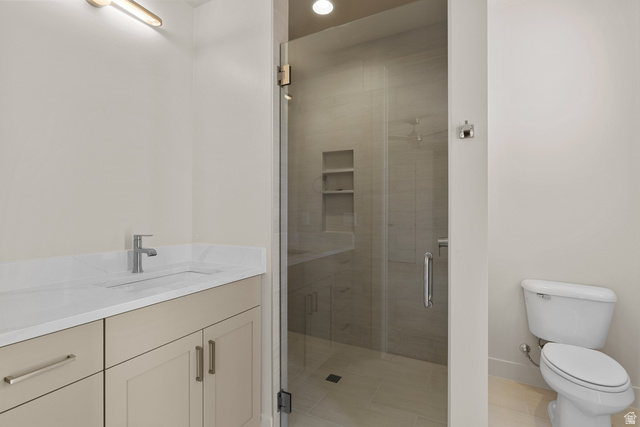 2955 East Rimrunner Drive St. George, UT 84790 - Photo 20 of 35 Bathroom featuring a glass-enclosed shower with integrated shelving, a single vanity with an undermount sink, a white countertop, and a contemporary wall-mounted light fixture