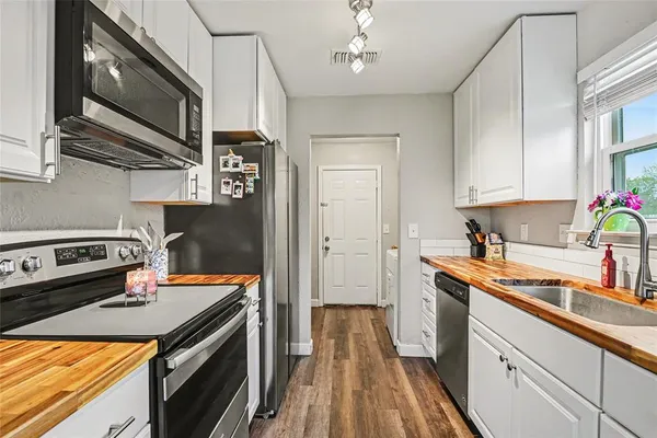 a kitchen with stainless steel appliances a stove a sink dishwasher and cabinets with wooden floor