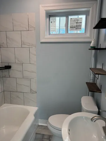 a white toilet sitting next to a bath tub