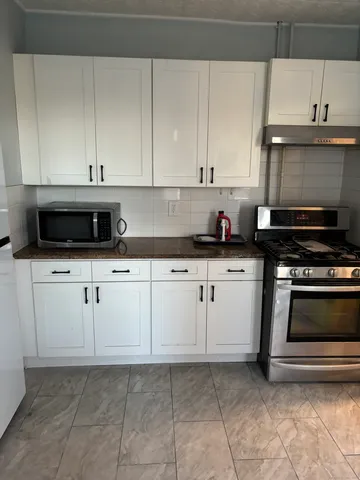 a kitchen with granite countertop white cabinets and stainless steel appliances