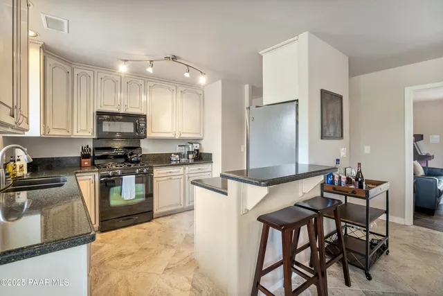 a kitchen with granite countertop a table chairs microwave and cabinets