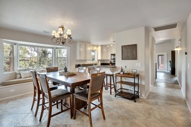 a view of a dining room with furniture a chandelier and large windows