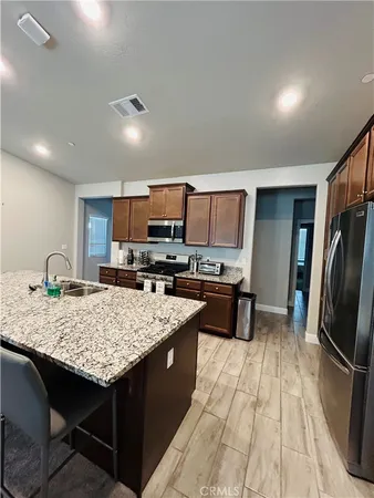 a kitchen with kitchen island granite countertop a sink stove refrigerator and wooden floor